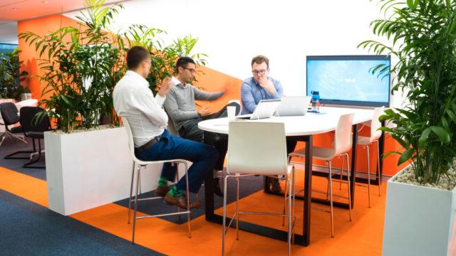 Three engineers sitting at a table having a discussion